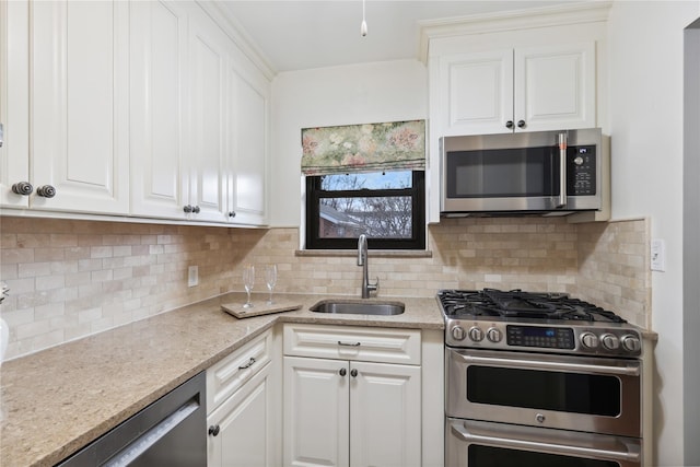 kitchen with light stone counters, appliances with stainless steel finishes, sink, and white cabinets