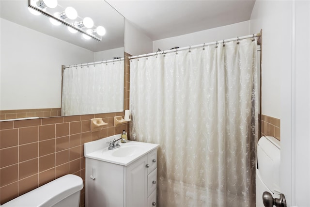 bathroom with tile walls, vanity, and toilet