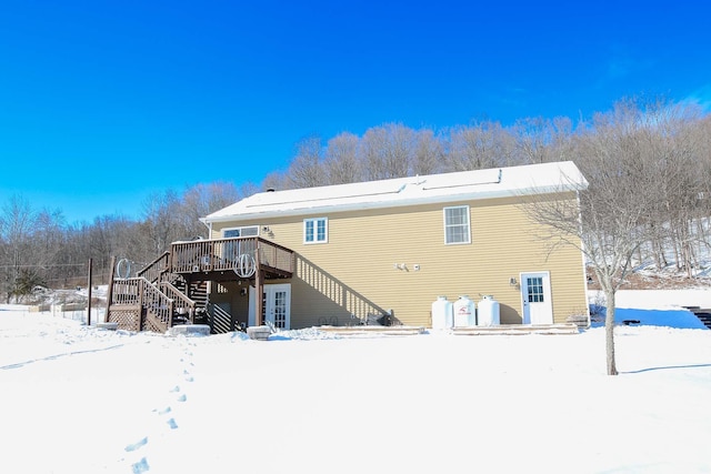 snow covered back of property with a wooden deck