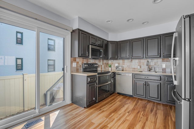 kitchen featuring sink, stainless steel appliances, a healthy amount of sunlight, and light wood-type flooring