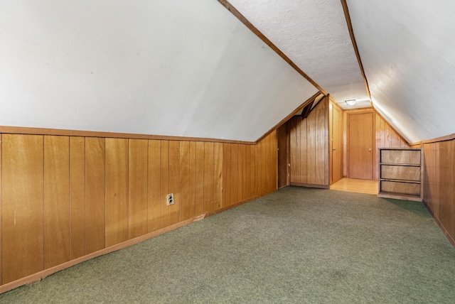 bonus room with light colored carpet, wooden walls, and vaulted ceiling