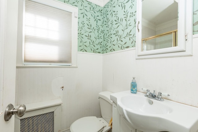 bathroom with crown molding, toilet, a shower with shower door, and sink