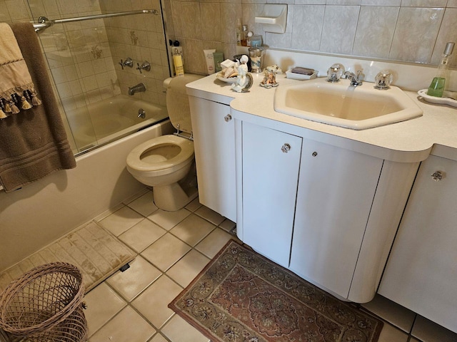 full bathroom featuring tile patterned flooring, tile walls, bath / shower combo with glass door, vanity, and toilet