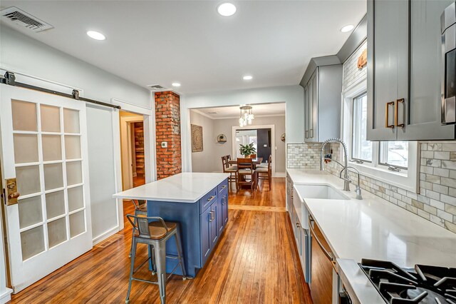 kitchen featuring sink, backsplash, a center island, a kitchen bar, and a barn door