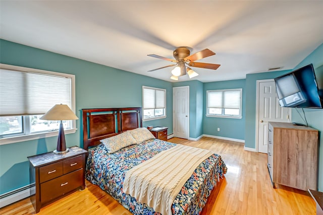 bedroom featuring a baseboard heating unit, ceiling fan, and light wood-type flooring