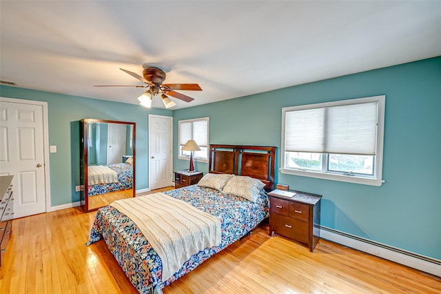 bedroom with multiple windows, a baseboard radiator, light hardwood / wood-style floors, and ceiling fan