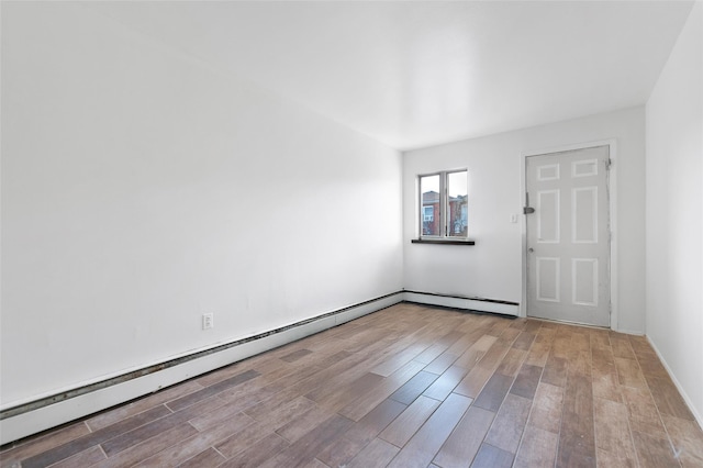 spare room with baseboard heating and light hardwood / wood-style flooring