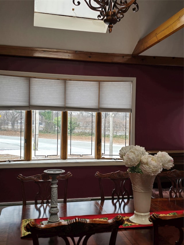 dining area with beam ceiling, a wealth of natural light, and a chandelier