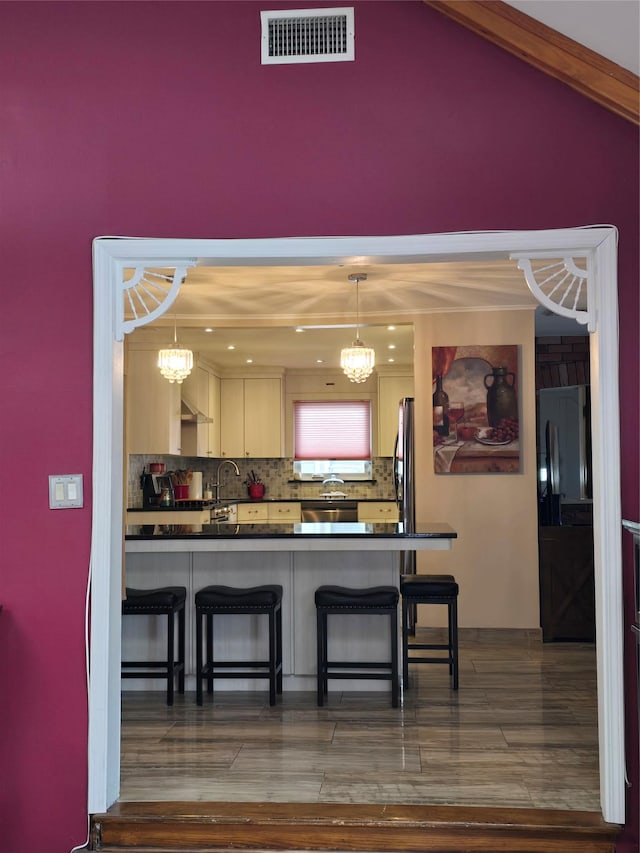 kitchen featuring sink, a breakfast bar, black refrigerator, dark hardwood / wood-style flooring, and decorative light fixtures