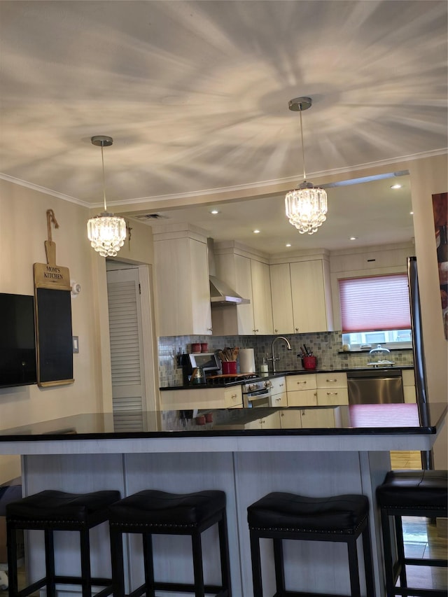 kitchen featuring pendant lighting, tasteful backsplash, stainless steel appliances, crown molding, and wall chimney range hood