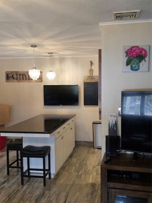 kitchen featuring pendant lighting, ornamental molding, and a breakfast bar area