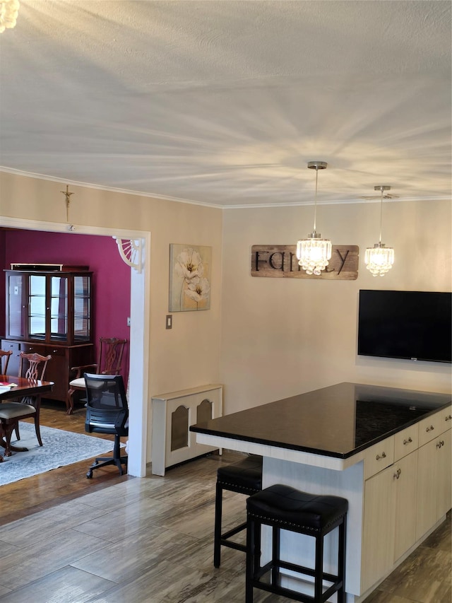 kitchen with hanging light fixtures, a textured ceiling, a breakfast bar area, and wood-type flooring