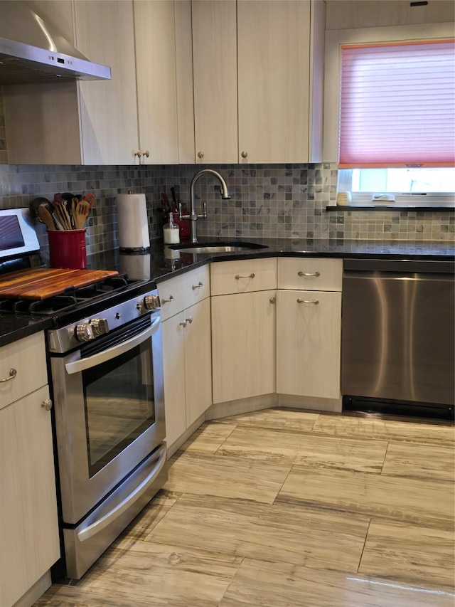 kitchen featuring ventilation hood, sink, backsplash, dark stone counters, and stainless steel appliances