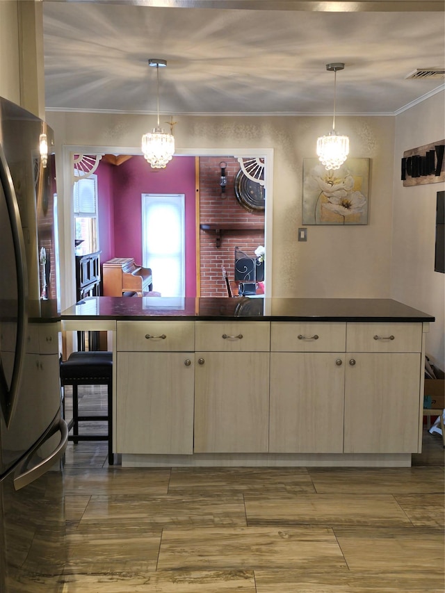 kitchen featuring stainless steel refrigerator, decorative light fixtures, crown molding, and a notable chandelier