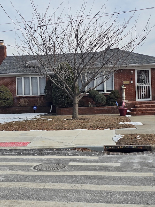 15731 80th St, Howard Beach, NY 11414 - view of front facade with roof with shingles, a chimney, and brick siding