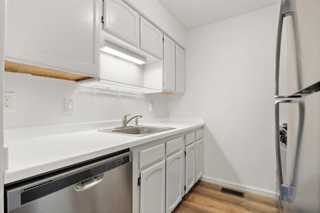 kitchen featuring white cabinetry, dishwasher, sink, fridge, and light hardwood / wood-style floors