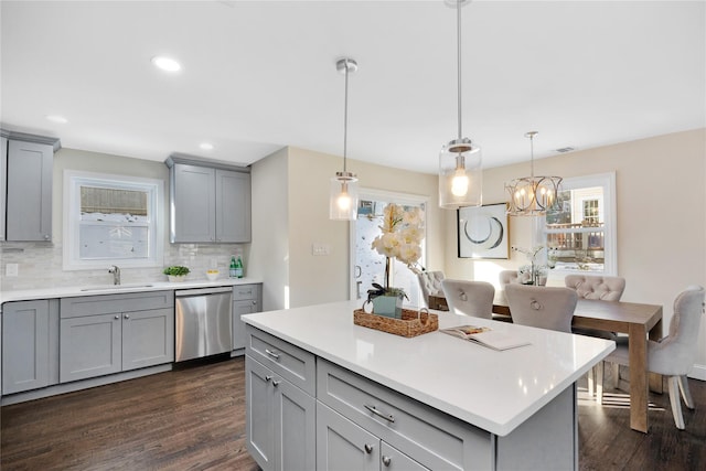 kitchen featuring gray cabinetry, sink, decorative light fixtures, and stainless steel dishwasher