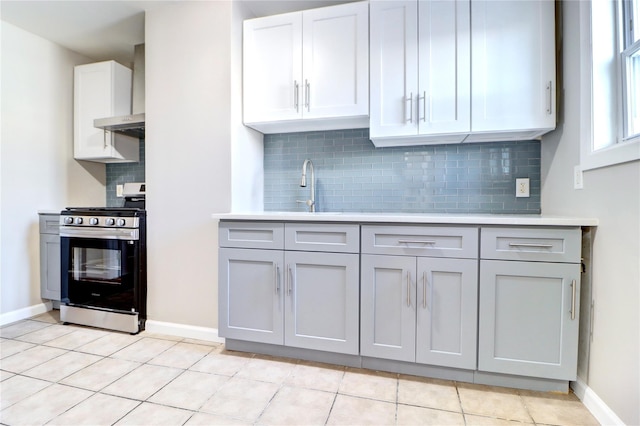 kitchen featuring light tile patterned flooring, white cabinetry, stainless steel gas range, and decorative backsplash