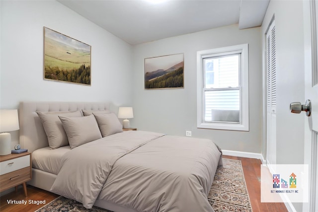 bedroom with dark hardwood / wood-style floors and a closet