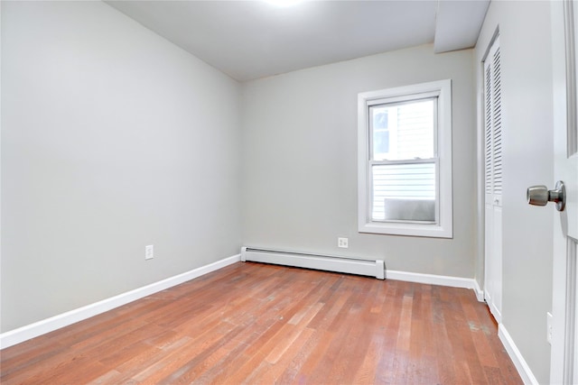 spare room featuring a baseboard heating unit and light hardwood / wood-style flooring