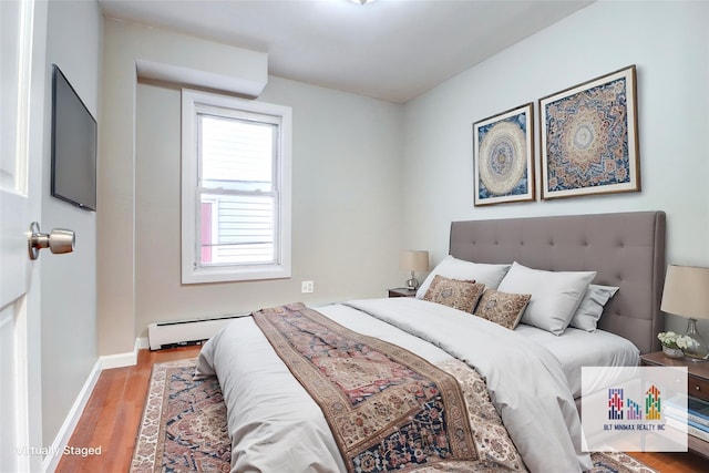 bedroom featuring wood-type flooring and a baseboard heating unit