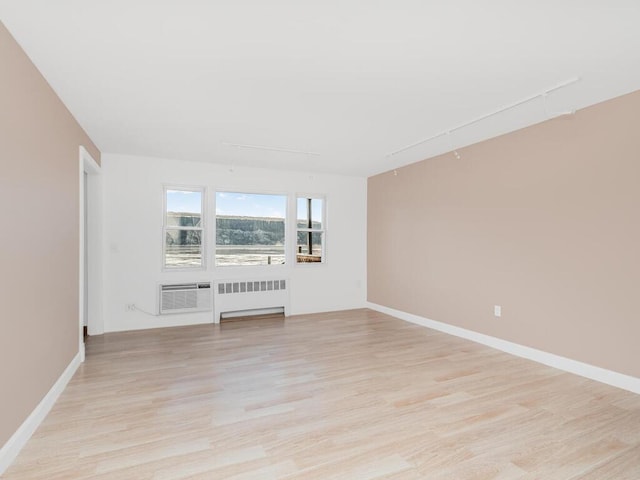 unfurnished living room featuring light hardwood / wood-style flooring, radiator heating unit, and track lighting