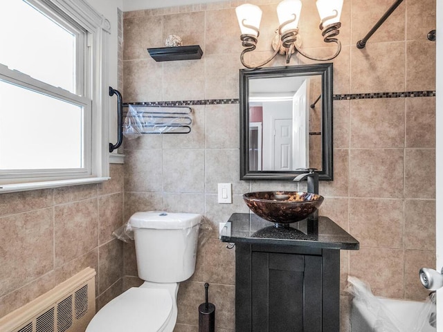 bathroom featuring tile walls, radiator heating unit, a chandelier, vanity, and toilet