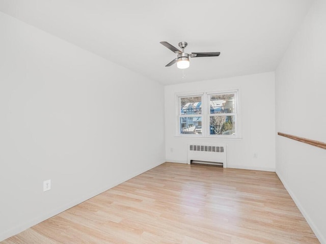 empty room featuring ceiling fan, radiator heating unit, and light wood-type flooring