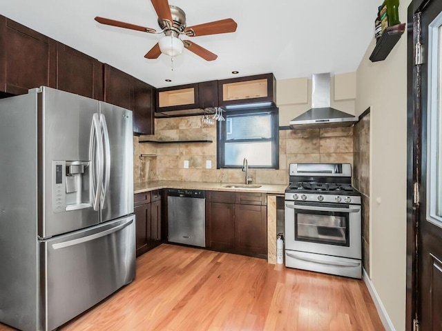 kitchen featuring appliances with stainless steel finishes, sink, decorative backsplash, light hardwood / wood-style floors, and wall chimney exhaust hood