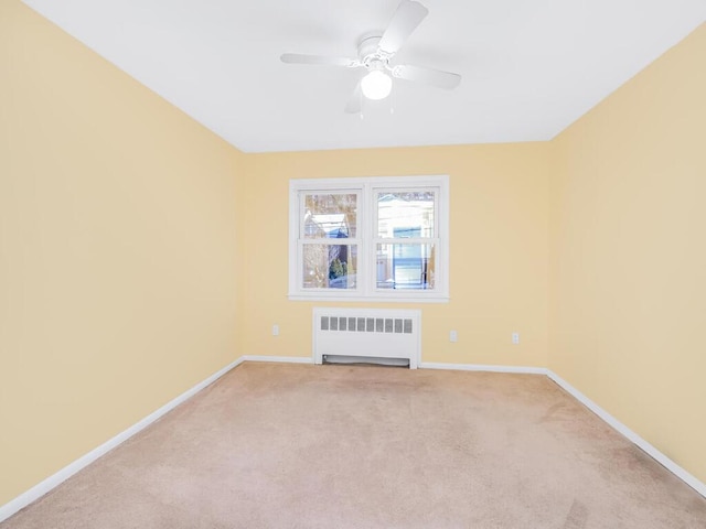 empty room with ceiling fan, radiator, and light carpet