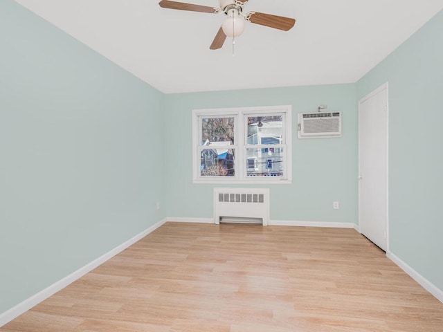 spare room featuring ceiling fan, radiator, a wall unit AC, and light wood-type flooring