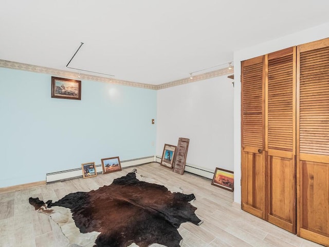 interior space with a closet, baseboard heating, and light wood-type flooring