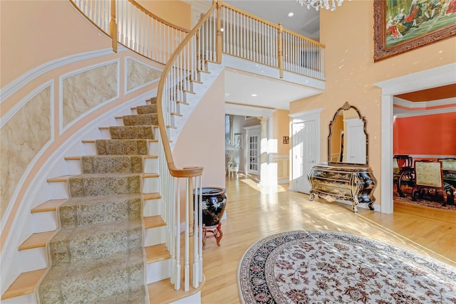 stairway with a notable chandelier, hardwood / wood-style flooring, and a towering ceiling