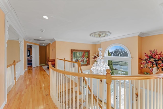 hall featuring crown molding, wood-type flooring, and a chandelier