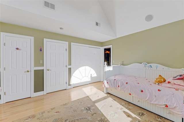 bedroom with wood-type flooring and vaulted ceiling