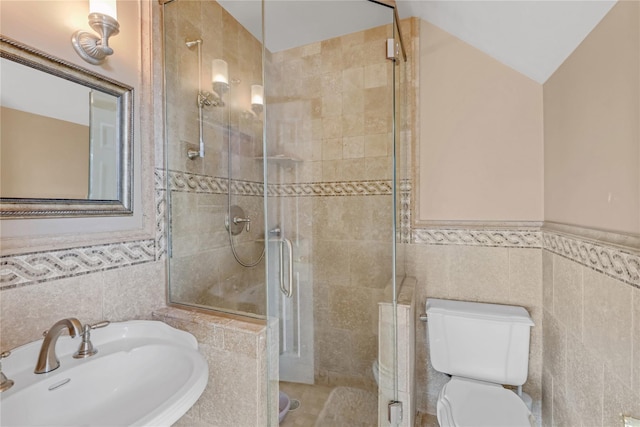 bathroom with toilet, an enclosed shower, sink, vaulted ceiling, and tile walls