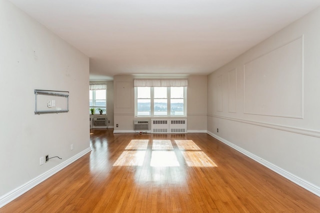 spare room with a wall mounted air conditioner, radiator, and hardwood / wood-style floors