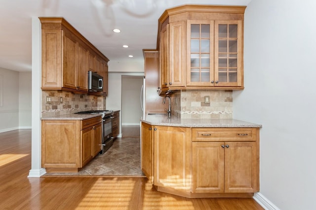 kitchen featuring black gas stove, sink, light stone countertops, and backsplash