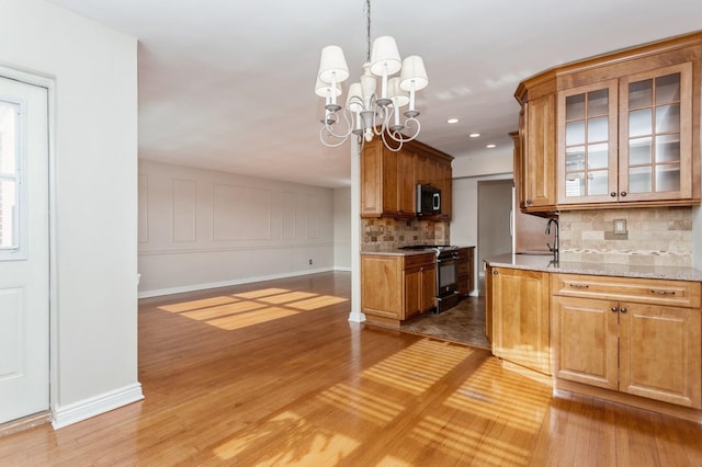 kitchen with tasteful backsplash, sink, light stone counters, black electric range, and light wood-type flooring