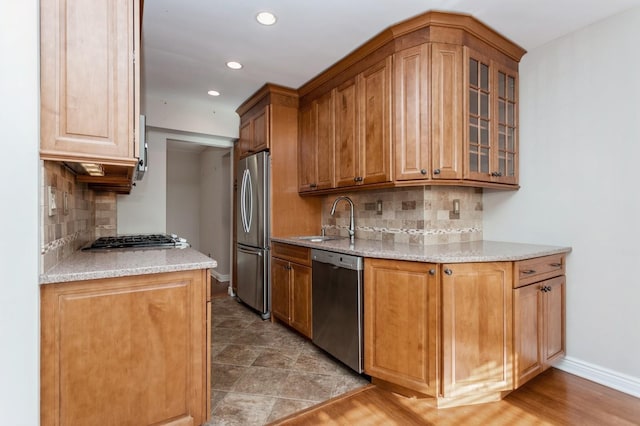 kitchen featuring stainless steel appliances, light stone countertops, sink, and decorative backsplash