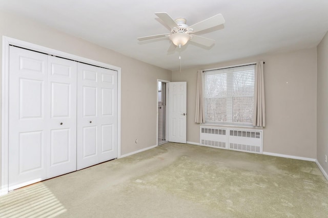 unfurnished bedroom featuring radiator, light colored carpet, ceiling fan, and a closet