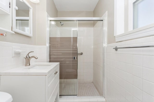 bathroom with vanity, tile walls, and a shower with shower door