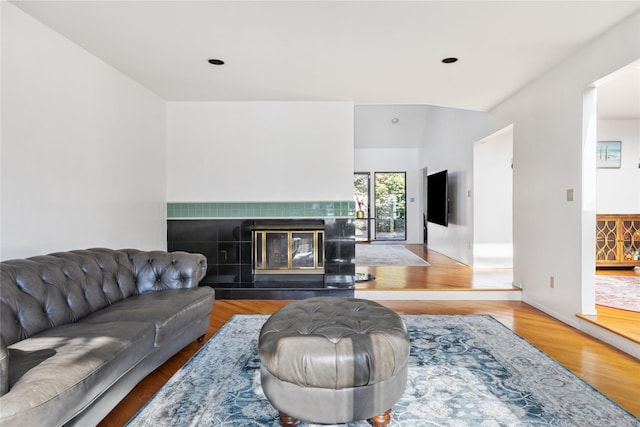 living room with wood-type flooring and a tile fireplace