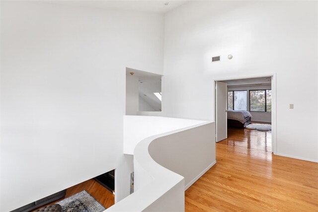 hallway with light hardwood / wood-style flooring and a high ceiling