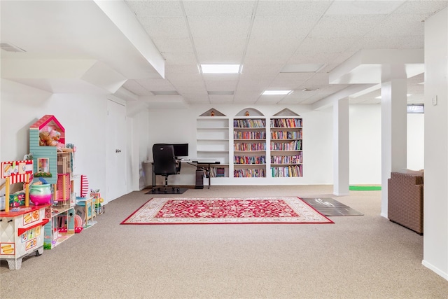 rec room with a paneled ceiling, carpet, and built in features