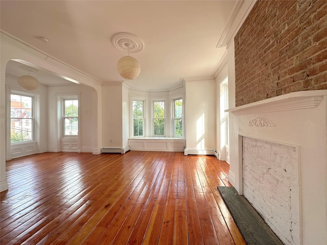 unfurnished living room featuring a healthy amount of sunlight, ornamental molding, hardwood / wood-style floors, and a baseboard heating unit