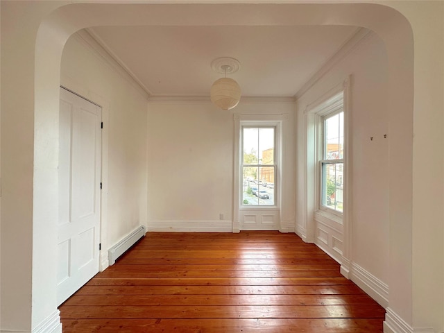 unfurnished room with a baseboard radiator, dark wood-type flooring, and crown molding