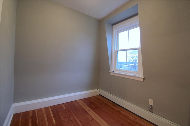 unfurnished room with a baseboard heating unit and hardwood / wood-style floors