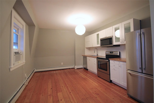 kitchen with sink, appliances with stainless steel finishes, butcher block counters, white cabinets, and light wood-type flooring