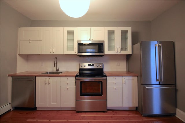 kitchen featuring stainless steel appliances, white cabinetry, sink, and butcher block countertops